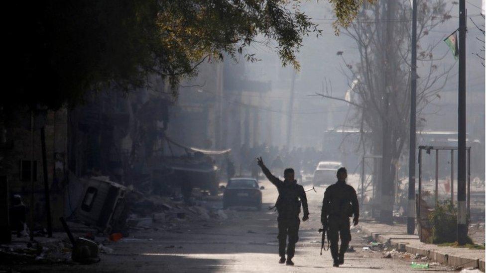 A member of forces loyal to Syria's President Bashar al-Assad gestures as he walks with his fellow fighter along a street in a government held area of Aleppo, Syria on 9 December 2016.