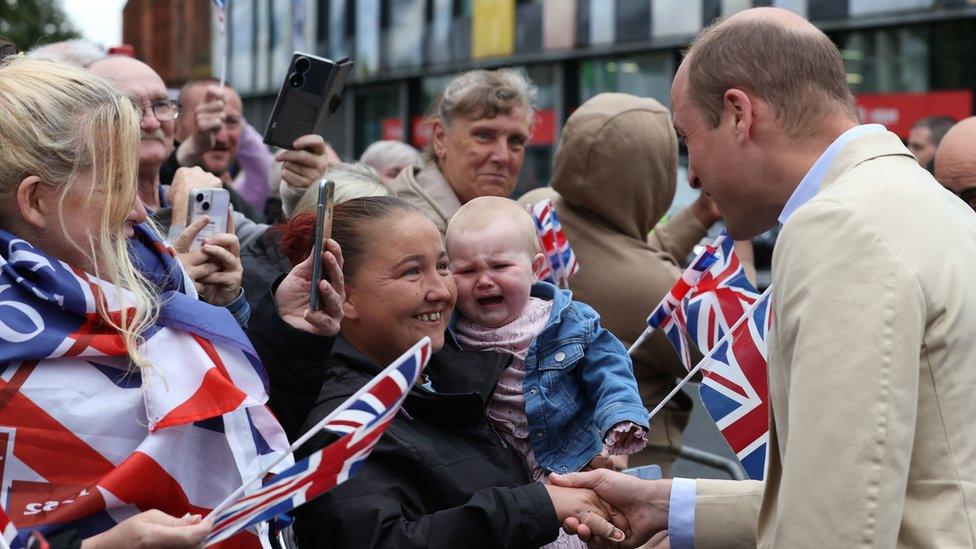 A baby girl cries as her mother shakes Prince William's hand in east Belfast