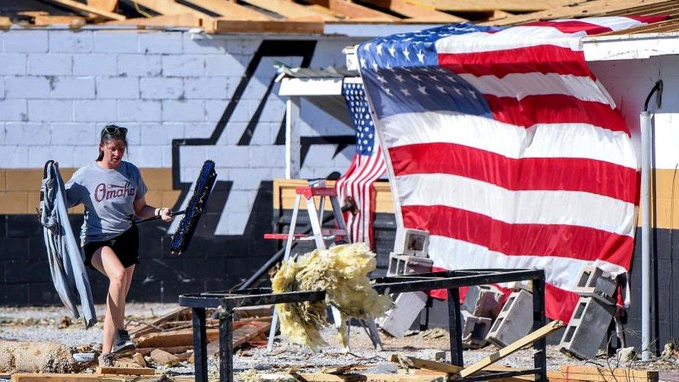 Brittany Pace looks through debris at the Amory High School baseball field the day after a tornado in Amory, Mississippi