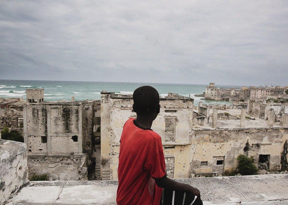 Boy looking over ruined buildings