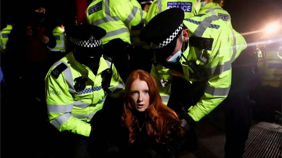 Police detain a woman as people gather at a memorial site in Clapham Common Bandstand