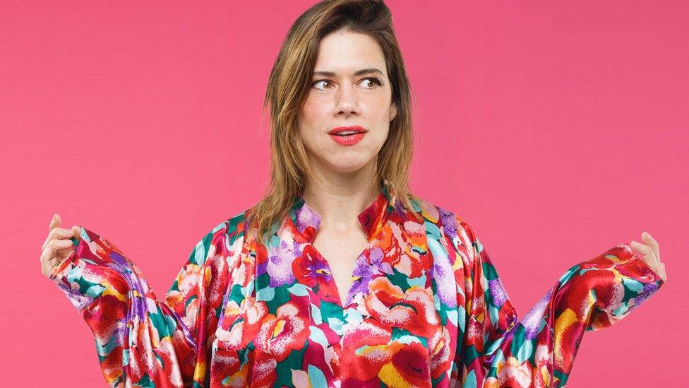 Lou Sanders in front of a pink background