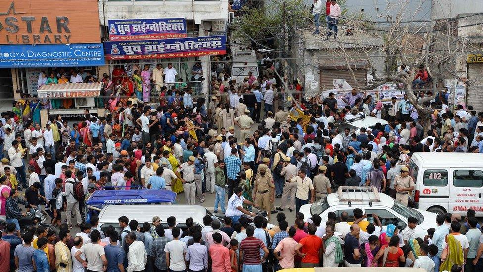 Onlookers gather along a road near the site where 11 family members were found dead inside their home in the neighbourhood of Burari in New Delhi on July 1, 2018.