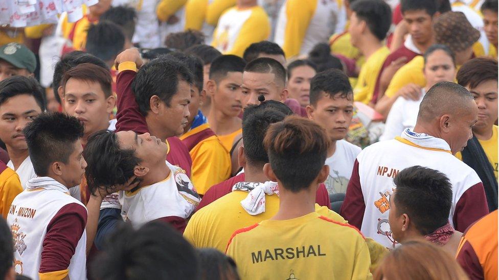 A devotee (centre) is carried by colleagues after collapsing due to exhaustion. 9 January 2017, Manila, Philippines.