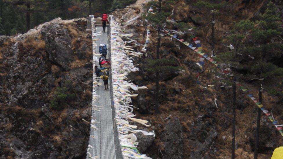 The team climb a wire suspension bridge