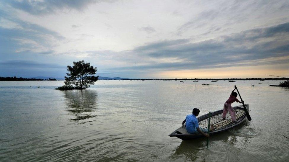 Youngster paddle through a landscape inundated by water in the flood affected Morigaon district of Assam state, India, 01 September 2015.