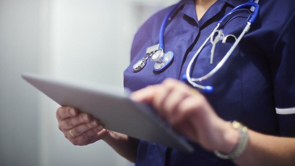 A nurse looks at a tablet