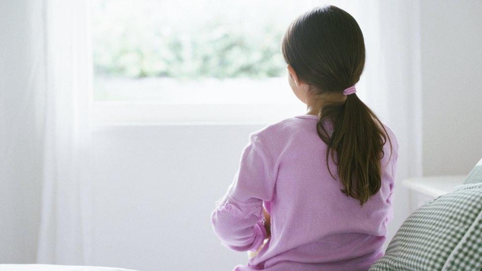 Stock photo of a girl sitting alone on a bed
