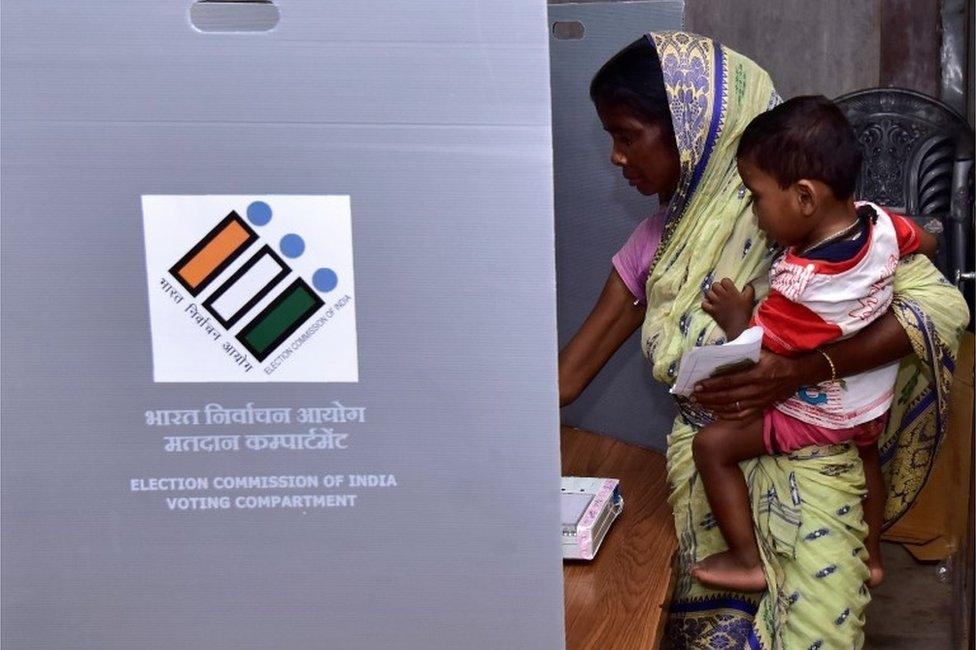 A woman holds a child as she casts her vote at a polling station during the second phase of general election in Hojai district in the northeastern state of Assam, India, April 18, 2019.