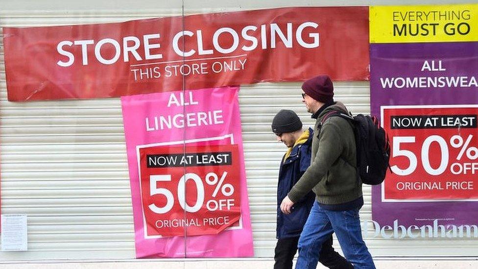 People walk by closed Debenhams shop