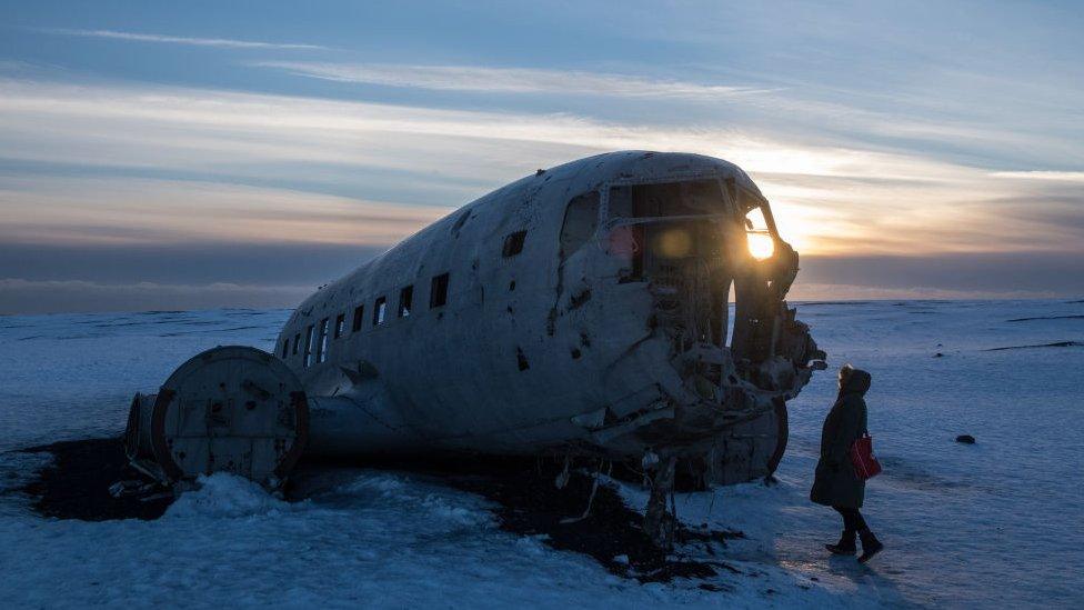 A woman looks at the remaining wreckage from the Sólheimasandur plane crash site in southern Iceland