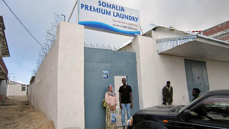 Mary Harper and Mohamed outside his dry cleaning business