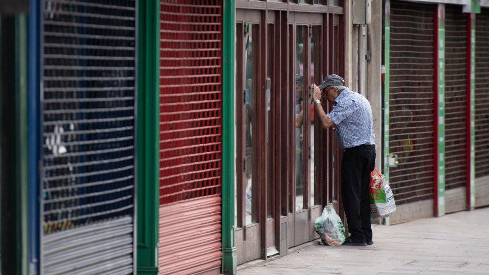 A man looks into the window of a closed coffee shop in Cardiff