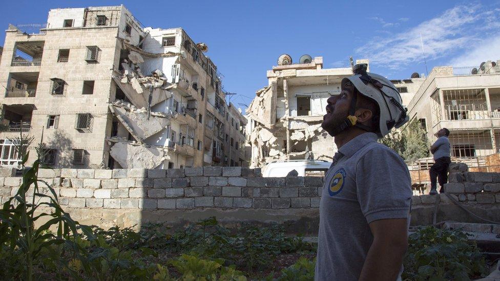 A Syrian rescuer looks towards the sky following an air strike in the rebel-held Ansari district in the northern Syrian city of Aleppo on September 23, 2016.