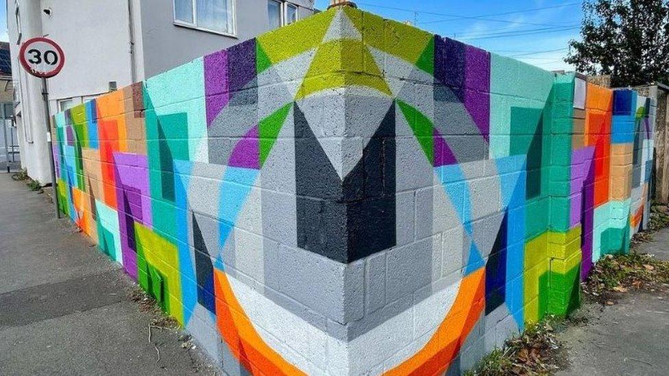 A wall with a brightly coloured, geometric mural