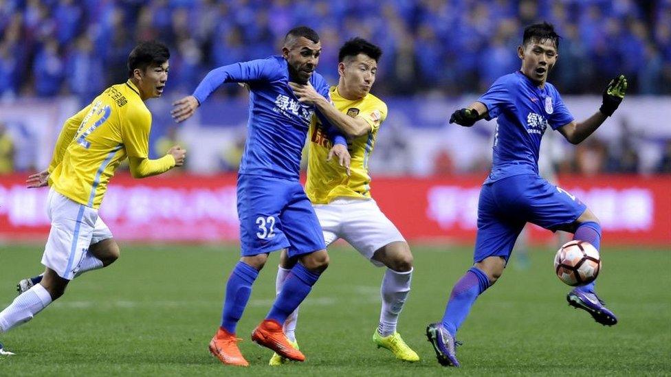 Shanghai Shenhua's Argentine striker Carlos Tevez (2L) fights for the ball with Yang Xiaotian (2R) of Jiangsu Suning during their Chinese Super League football match in Shanghai on March 5, 2017