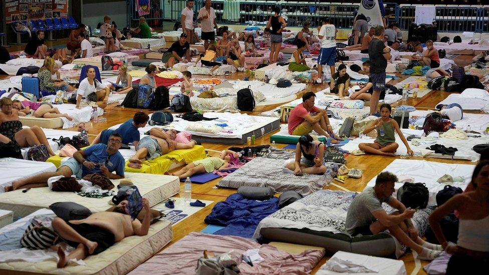 Tourists being sheltered in a sports hall after being evacuated from their accommodation after a wildfire on the island of Rhodes