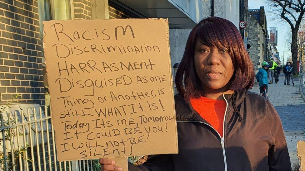 Paula with a placard about how she is treated