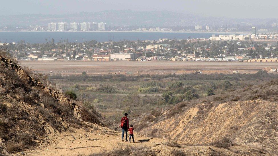 A man and a child walk after crossing illegally to the US as seen from Tijuana, Mexico