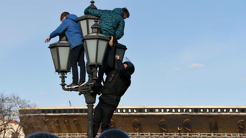 Teenagers climbing a lamp post at a protest in Moscow in March