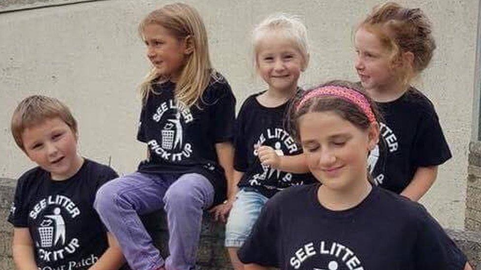 Children from the litter picking group sit on a wall