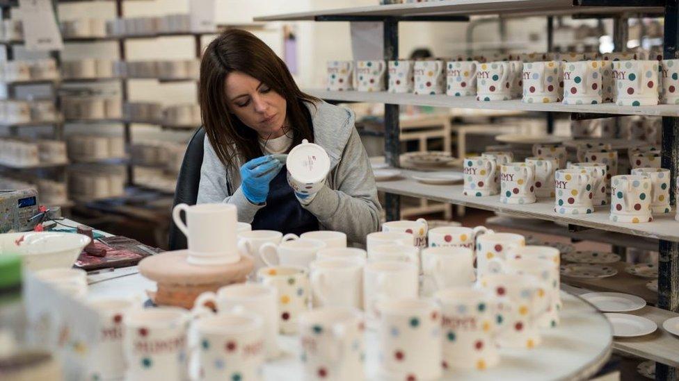 A worker hand-paints crockery in a factory