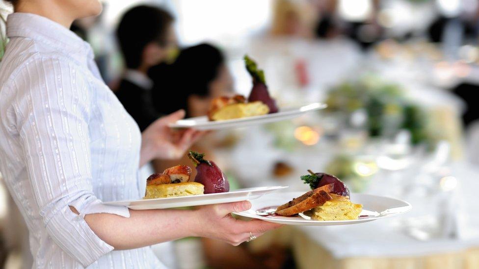 Waitress carrying three plates.