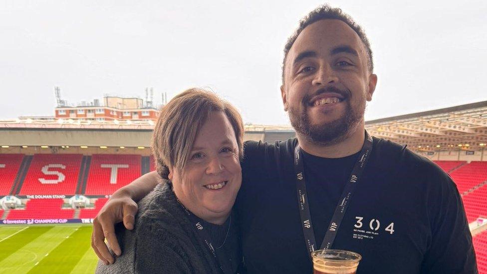 Clare Joseph and Ellis Joseph smiling as they embrace in a sports stadium