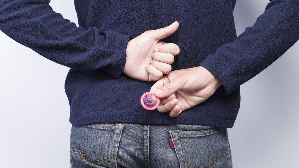 A man holding a condom behind his back