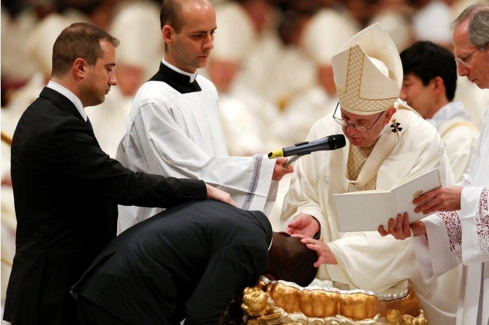 Pope Francis baptizes a man as he leads the Easter vigil mass in Saint Peter's Basilica at the Vatican