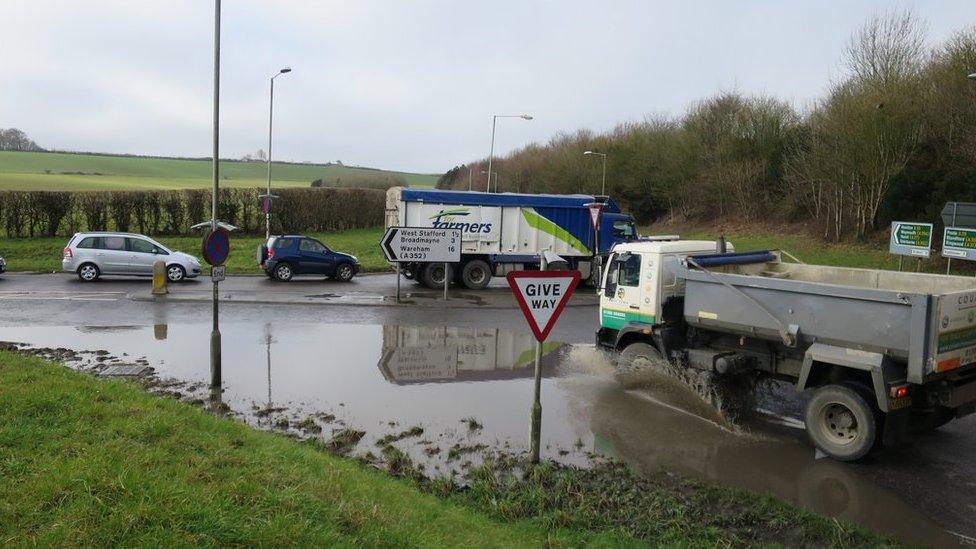 Cars and lorries driving through floodwater on the A35