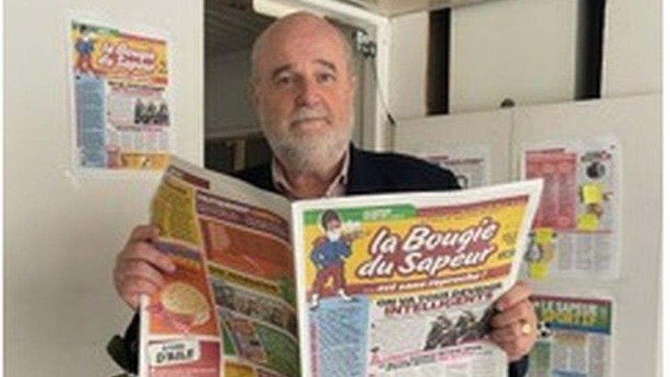 Jean d'Indy holding a copy of the newspaper