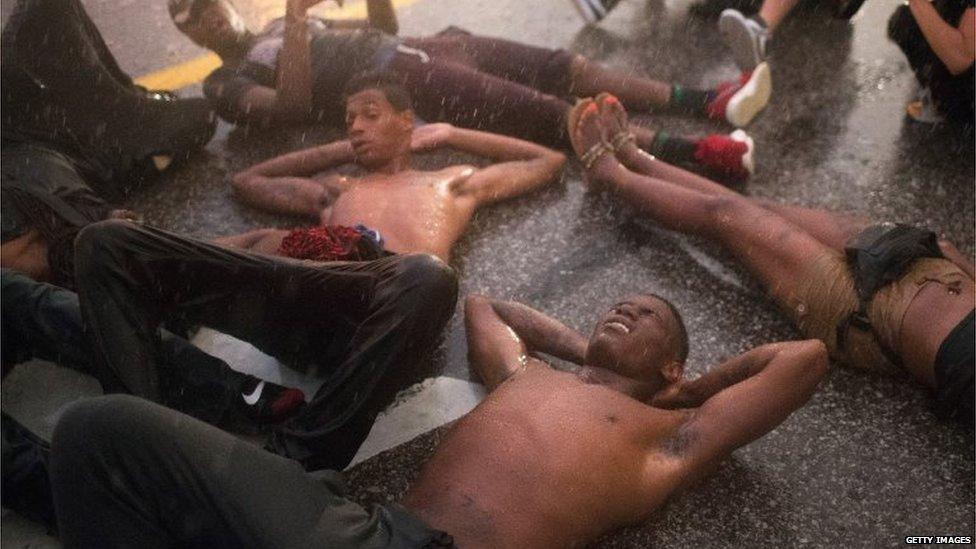 Demonstrators, marking the one-year anniversary of the shooting of Michael Brown, stage a die in along West Florrisant Street in a driving rain on August 9, 2015 in Ferguson, Missouri.