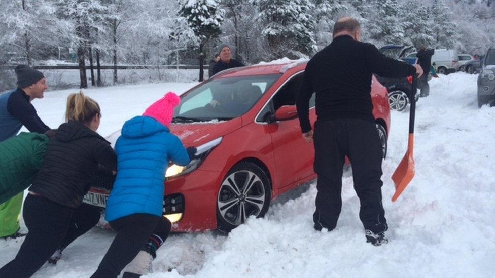 People pushing car in snow