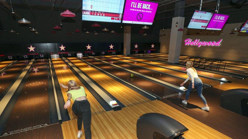 People bowling with empty lanes between them