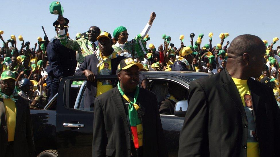 Robert Mugabe (L in car) waves as he arrives to address crowds gathered during an election campaign rally held at Chibuku Stadium, in Chitungwiza on July 16, 2013.