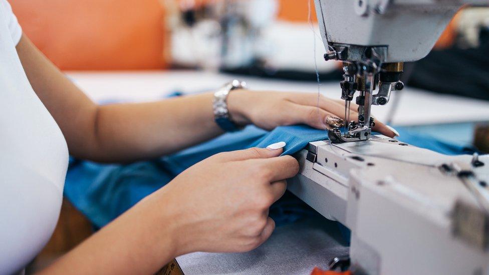 Close up shot of professional seamstress hands working in tailoring or sewing industry production hall.