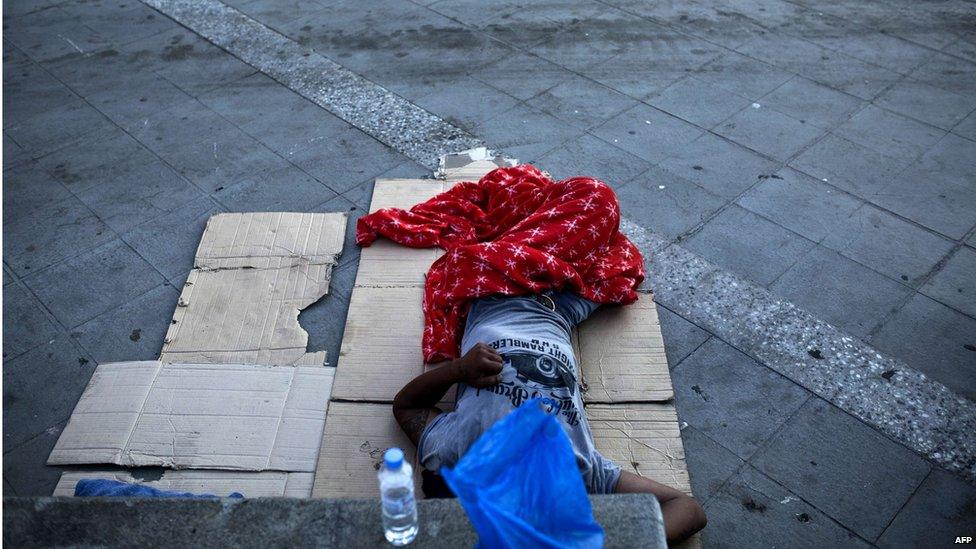 A homeless sleeps on the street near Omonia square in Athens on July 7, 201