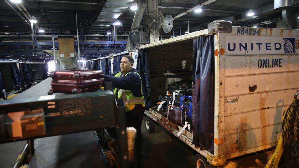 A baggage handler loads luggage after it was screened in a new explosives detection system at the Newark Liberty International Airport on May 1, 2014 in New York City.