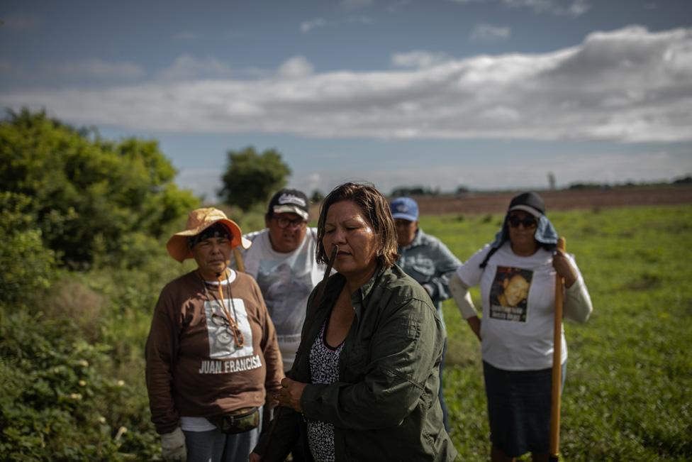 Mirna Medina smells an iron stick after piercing the ground with it, hoping she can detect the smell of decomposition