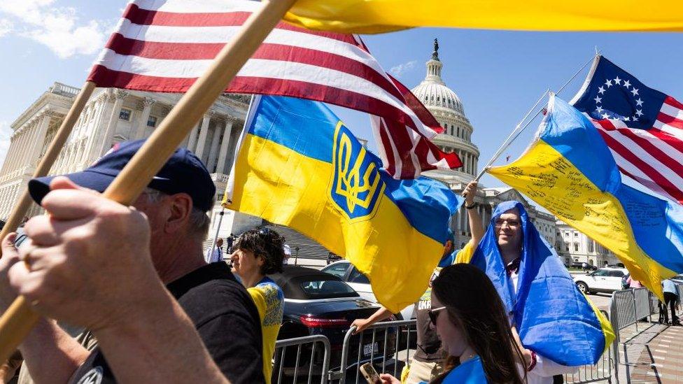 Supporters of Ukraine wave US and Ukrainian flags outside the US Capitol after the House approved foreign aid packages to Ukraine