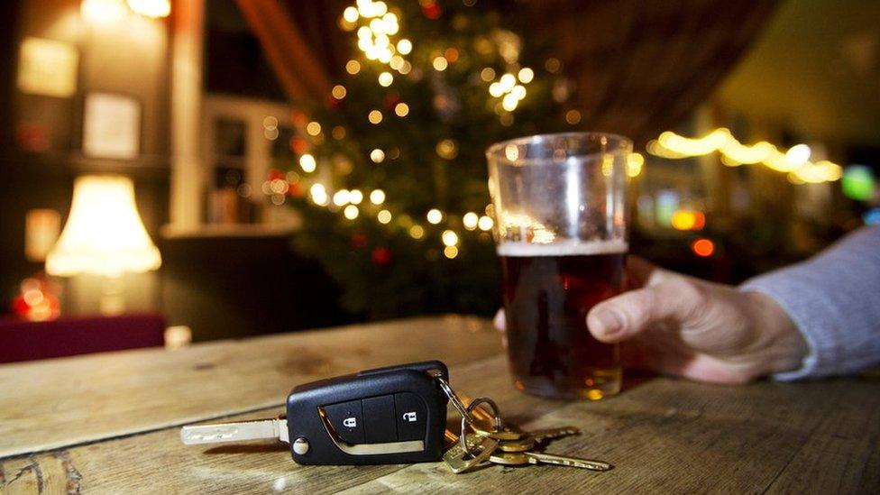 A man drinks a pint of beer while his car keys sit on a bar top