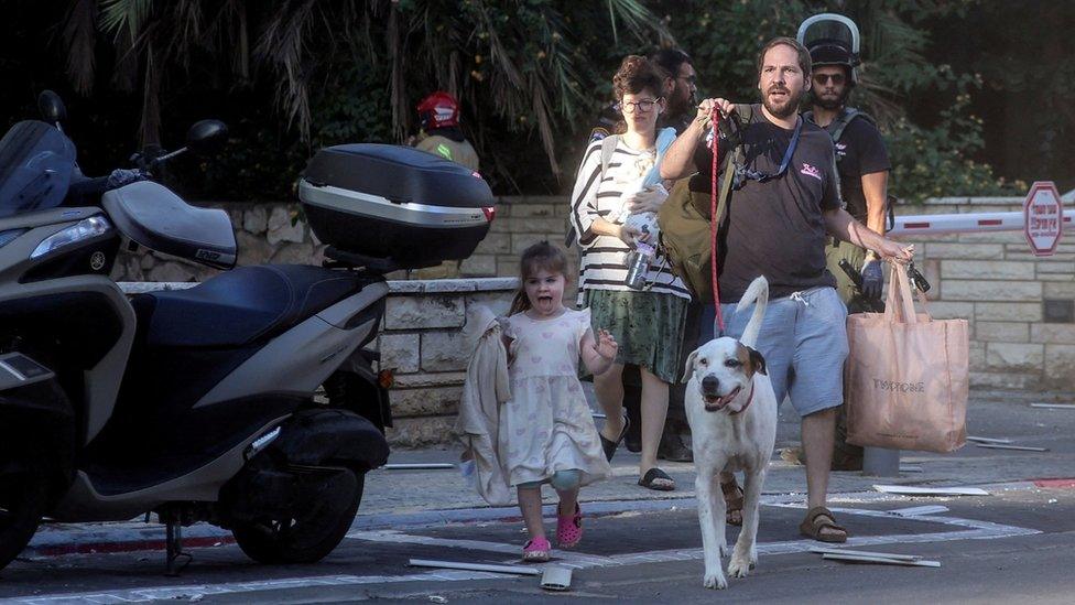 Israelis react on a street as rocket attacks are launched from the Gaza Strip, in Tel Aviv, Israel October 7, 2023