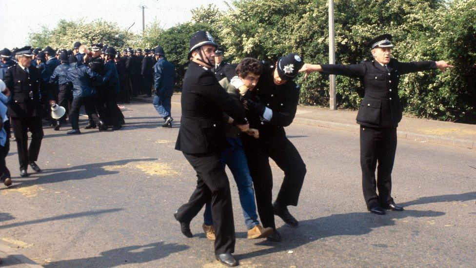 Striking miner being carried off by two policemen