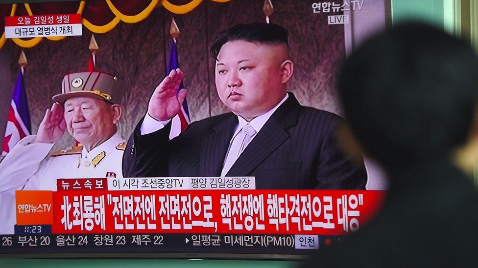 A man watches a television news broadcasting live footage of a military parade in Pyongyang on 15 April.