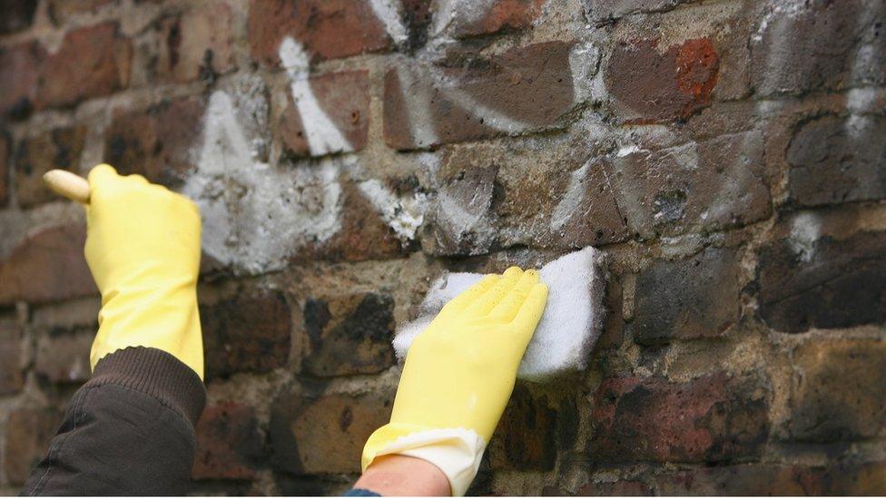 Youths cleaning a wall on a community payback scheme