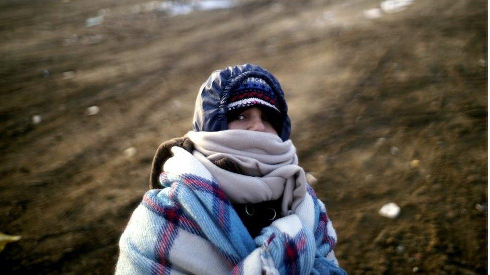 A migrant child wrapped in blankets tries to keep warm near the Macedonian-Serbian border