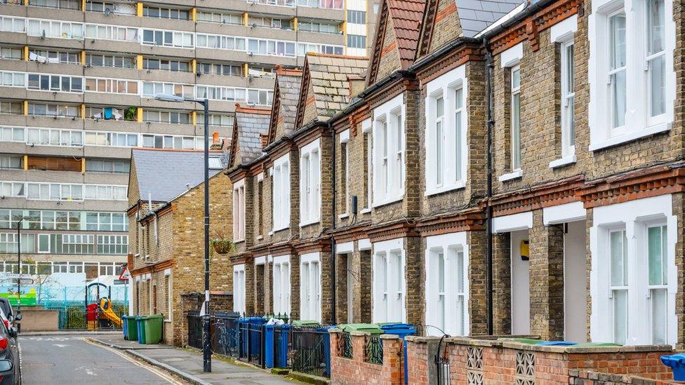 A row of terraced houses sits in front of a large tower block in east London.