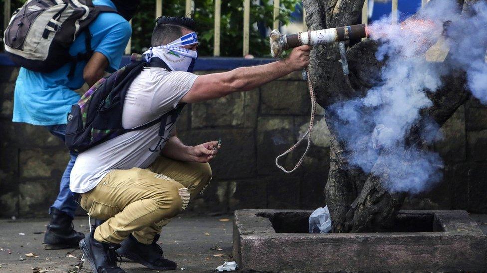 A protester fires a homemade mortar during clashes with riot police. The small welded tubes are hand-held