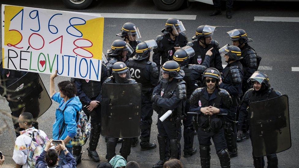 A man holds a placard reading "1968-2018 Revolution" in front of French CRS riot police at Tolbiac university site, branch of Paris 1 university, 20 April 2018